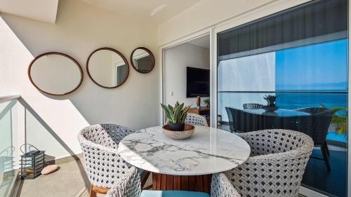 a dining room with a table and chairs and mirrors at Oceanfront 1BR with Balcony - Sea View & Pools in Puerto Vallarta