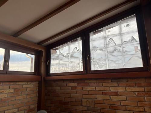 three windows in a room with a brick wall at Maya Apartman in Szeged