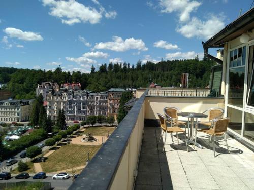 a balcony with a table and chairs and a city at Hotel Flora in Mariánské Lázně