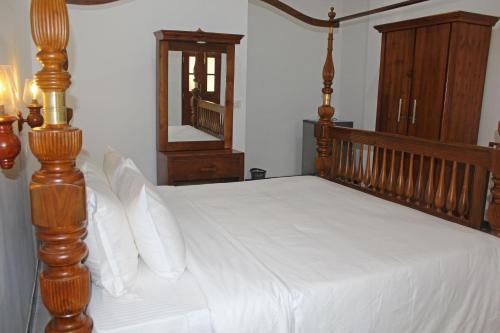 a bedroom with a wooden bed with white sheets and a mirror at Charika Villa in Bentota