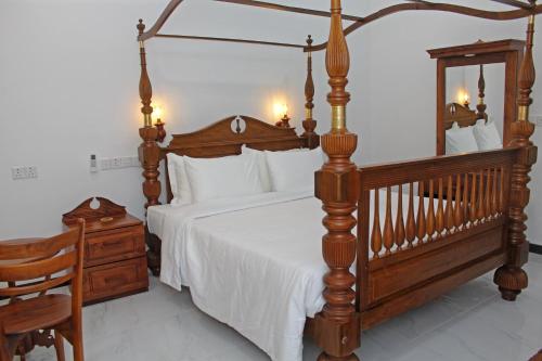 a bedroom with a large bed with a wooden frame at Charika Villa in Bentota