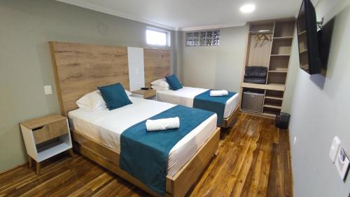 two beds in a room with wooden floors at Hotel Entre Brumas in Aguadas