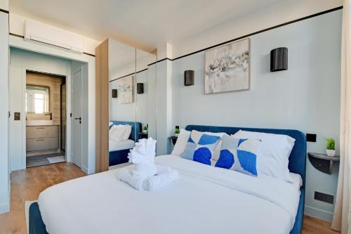 une chambre avec un grand lit blanc avec des oreillers bleus dans l'établissement La Maison Bizot 53 T3 by ecoflats, à Paris