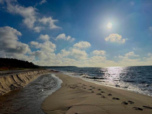 a beach with footprints in the sand and the ocean at Hotel Skovly in Rønne