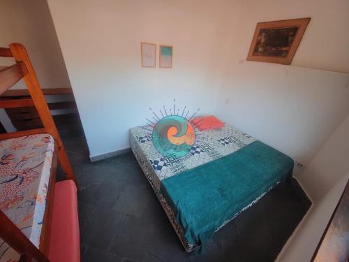 a small bedroom with a bed with a colorful blanket at Pousada Guaruondas in Guarujá