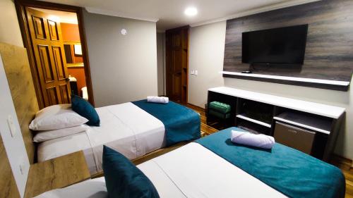 a hotel room with two beds and a flat screen tv at Hotel Entre Brumas in Aguadas