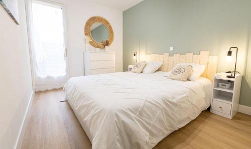 une chambre blanche avec un grand lit et un miroir dans l'établissement T2 à l'Ile Rousse proche mer et centre, à LʼÎle-Rousse