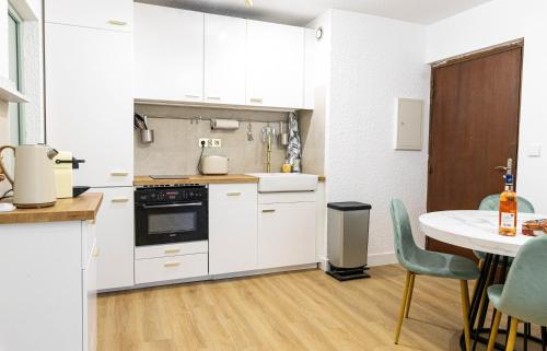 une cuisine avec des armoires blanches et une table et des chaises dans l'établissement T2 à l'Ile Rousse proche mer et centre, à LʼÎle-Rousse