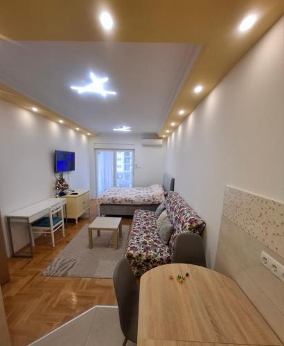 Una sala de estar con un sofá, una cama y una mesa. en Sun place, en Trebinje