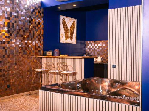 a bath tub in a bathroom with blue walls at Le Voluptueux - Sauna - Jacuzzi - Centre-Ville in Angers