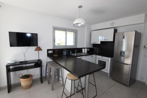 Il comprend une cuisine équipée d'une table noire et d'un réfrigérateur. dans l'établissement T2 centre-ville de Porto-Vecchio, à Porto-Vecchio