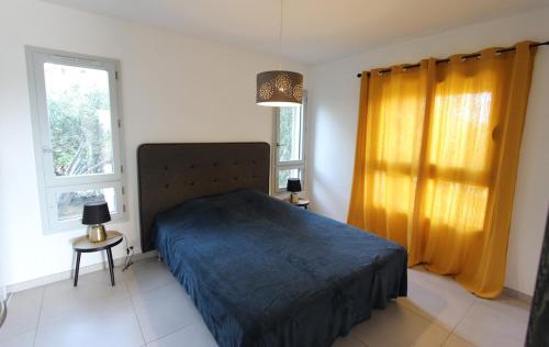 une chambre avec un lit bleu et deux fenêtres dans l'établissement T2 centre-ville de Porto-Vecchio, à Porto-Vecchio