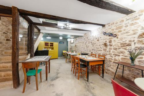 un restaurant avec des tables et des chaises en bois et un mur en pierre dans l'établissement La Bastide de Cordes, à Vindrac-Alayrac