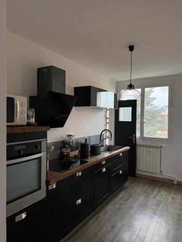 d'une cuisine avec des placards noirs, un évier et une fenêtre. dans l'établissement Lumineux appartement en centre ville, à Saint-Raphaël