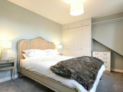 a bedroom with a white bed with a furry blanket on it at East Farm Croft in Alnwick