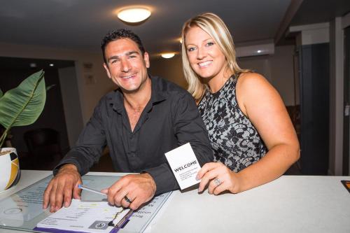 a man and a woman sitting at a table with a computer at Gladstone Reef Hotel Motel in Gladstone