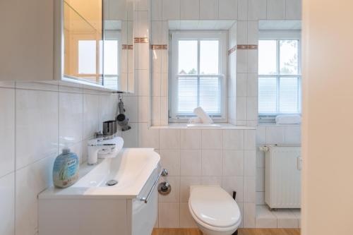 Un baño blanco con inodoro y lavabo. en Ahoi, en Sankt Peter-Ording