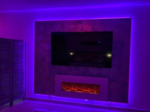 un salon avec une cheminée et des lumières violettes dans l'établissement Suite Dream, à Montigny-lès-Cormeilles