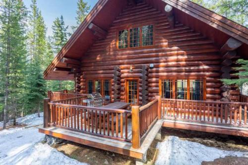 a log cabin with a large deck in the woods at Ravenwood Cabin by StayIn in Panorama
