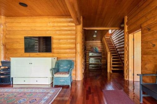 a living room with wooden walls and a staircase in a cabin at Ravenwood Cabin by StayIn in Panorama