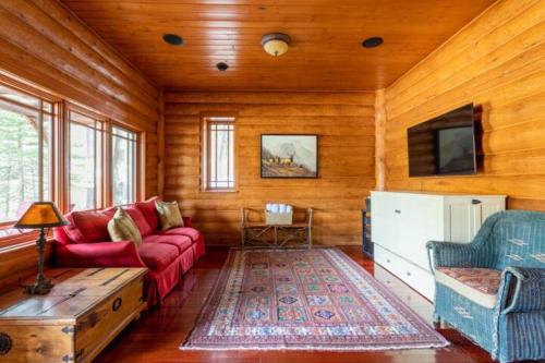 a living room with a red couch and a table at Ravenwood Cabin by StayIn in Panorama