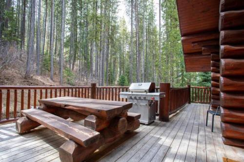 a wooden deck with a picnic table and a grill at Ravenwood Cabin by StayIn in Panorama