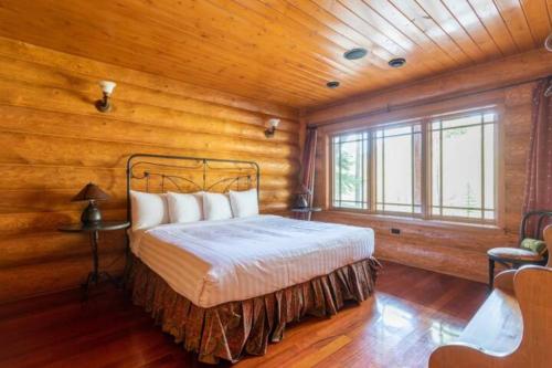a bedroom with a bed in a room with wooden walls at Ravenwood Cabin by StayIn in Panorama