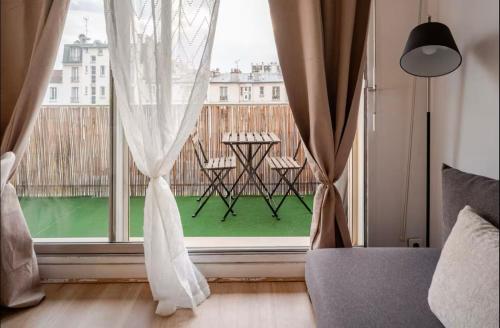 Cette chambre dispose d'un balcon avec une grande fenêtre et une table. dans l'établissement Paris in the center of Paris, à Paris