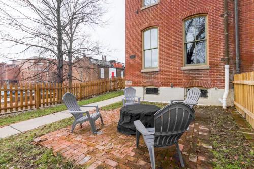 three chairs and a table in front of a brick building at Walk to Anheuser-Busch Brewery St Louis Escape! in Soulard