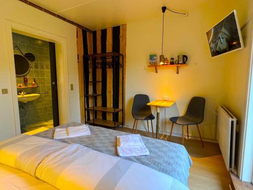 a bedroom with a bed and two chairs and a table at Hotel Skovly in Rønne