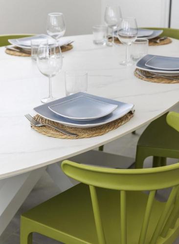 a table with plates and glasses and a green chair at Casa Blue Marlin in Kralendijk