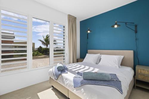 a bedroom with a large bed with a blue wall at Casa Blue Marlin in Kralendijk