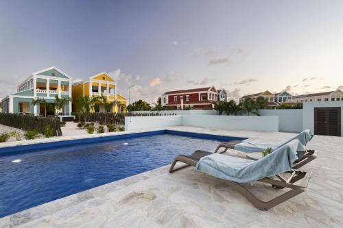 a swimming pool with a chaise lounge next to a house at Casa Blue Marlin in Kralendijk