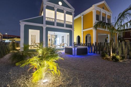 a yellow and white house with blue lights at Casa Blue Marlin in Kralendijk