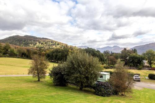 a rv parked in a field with mountains in the background at Sandpiper Caravan in Onich