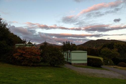 a small building on a field with a road at Sandpiper Caravan in Onich