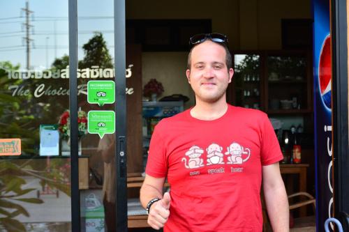 a man in a red shirt standing in front of a store at The Choice Hotel - Adults Only in Bangkok