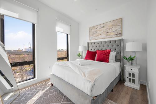 a white bedroom with a large bed with red pillows at Luxury Furnished Apartment Near Logan Airport in Boston