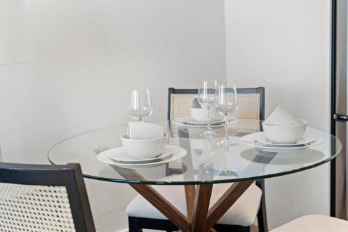 a glass table with glasses and plates and chairs at Luxury Furnished Apartment Near Logan Airport in Boston