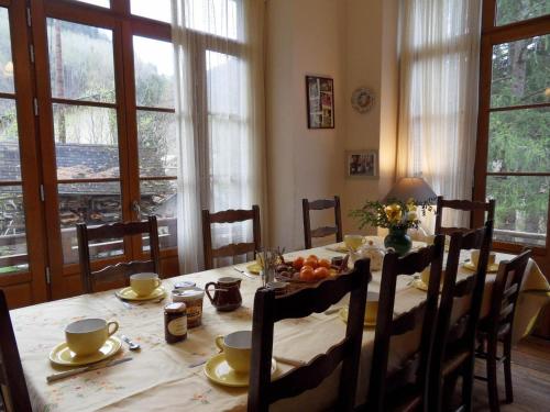 a dining room table with chairs and a table with food on it at La Chaumière, Formule maison entière in Colmars
