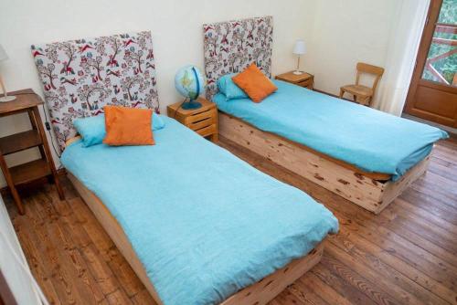 a bedroom with two beds with blue sheets and wooden floors at La Chaumière, Formule maison entière in Colmars