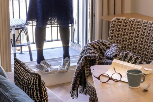 a woman standing on a window sill with glasses on a table at Hotel Louvre Montana in Paris