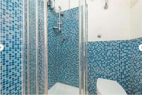 a blue tiled bathroom with a toilet and a shower at Casa Lella in Costa Rei