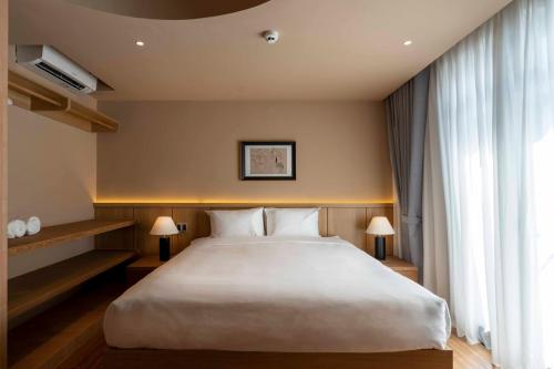 a bedroom with a large white bed and a window at DP Hotel in Tây Ninh