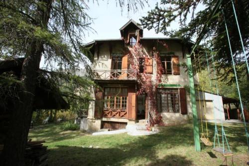 an old house with a tree in front of it at La Chaumière, Formule maison entière in Colmars