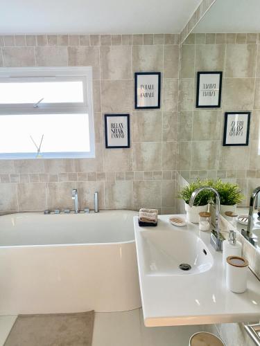 a white bathroom with a tub and a sink at Seaview Cottage on the Island in Millbay
