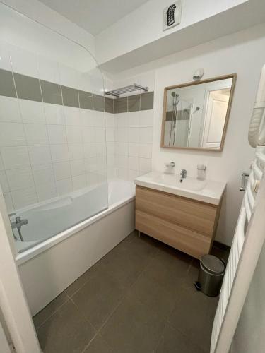 une salle de bain avec une baignoire, un lavabo et un miroir dans l'établissement Appartement T3 au Bord du Lac, à Parentis-en-Born