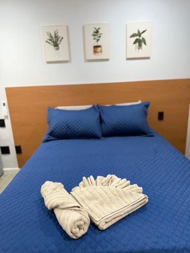 a bed with a blue comforter and a towel on it at Juca Studio Botafogo in Rio de Janeiro