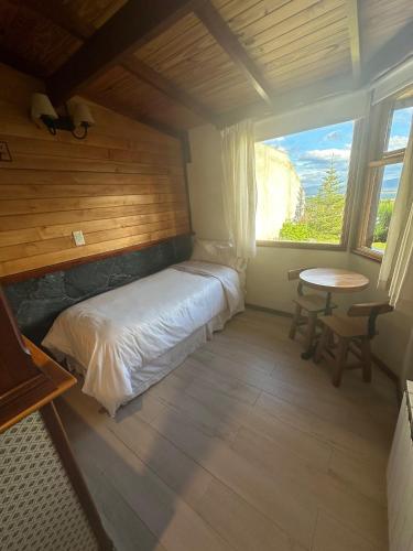 a bedroom with a bed and a table and a window at Ushuaia Lodge in Ushuaia