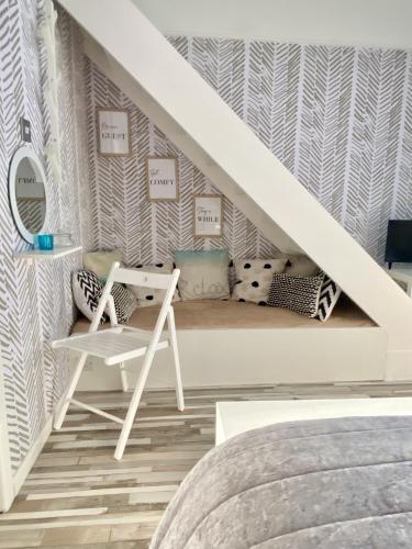a room with a bed and a chair under the stairs at Seaview Cottage on the Island in Millbay